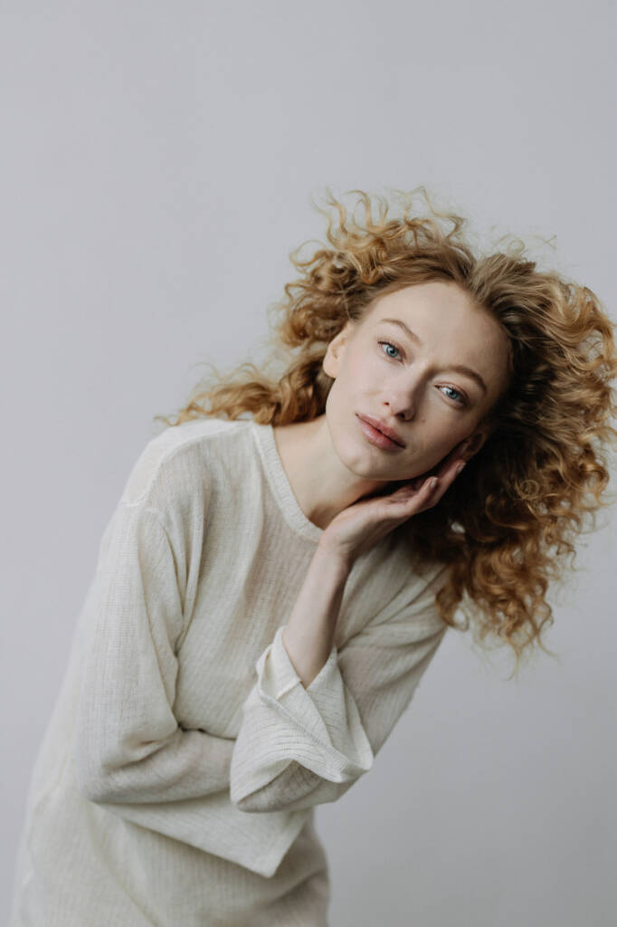 Portret kobiety z kręconymi włosami, głowa oparta na dłoni
